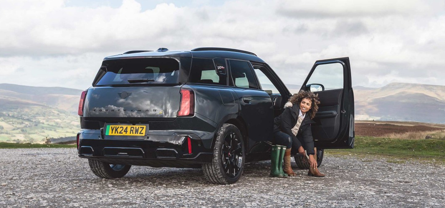 Rear view of the all-electric MINI Countryman in Smokey Green and Vibrant Silver roof parking. 